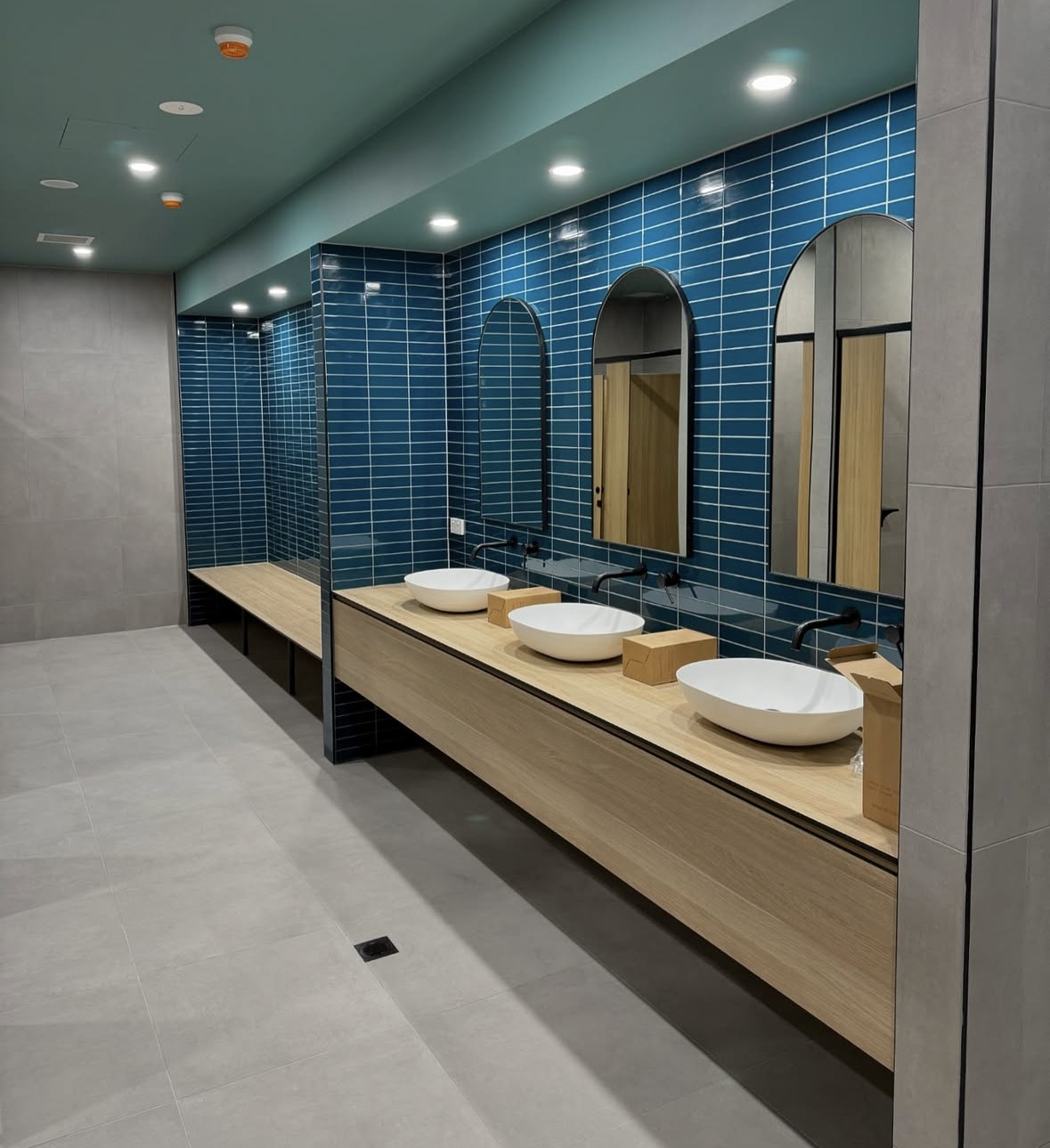 Blue-Tiled Commercial Amenities: Blue wall tile, arched openings and a long vanity define this commercial amenities fit-out.