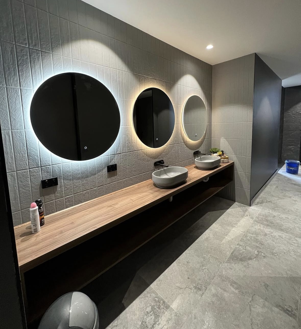 Commercial Feature Wall & Fit-Out: A long feature wall and vanity run tiled for a commercial fit-out, built around mirrored lighting.