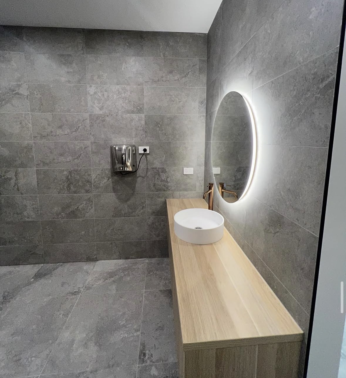 High-End Residential Ensuite: A monochrome residential ensuite with a round mirror and warm timber joinery.