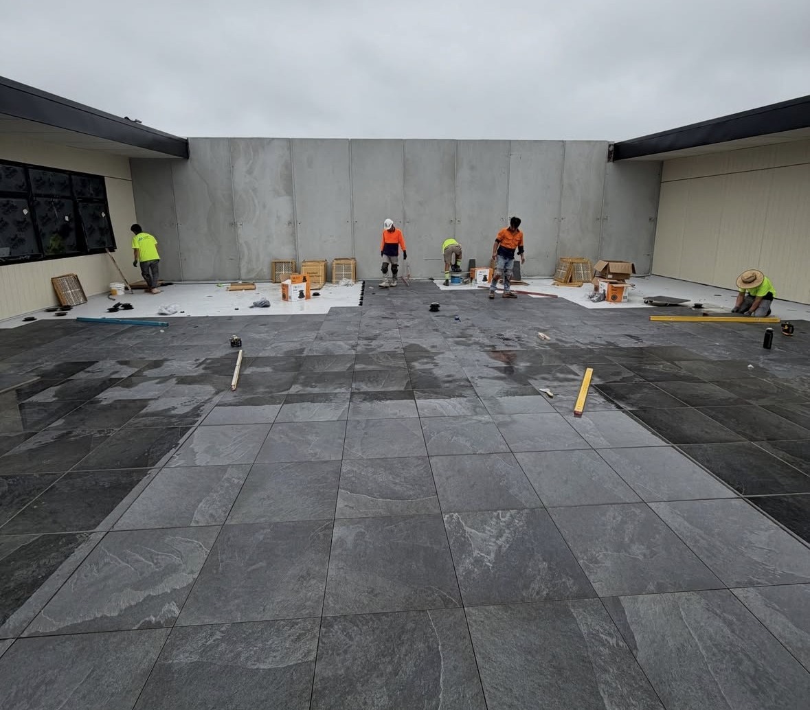 Monoid crew installing paving across an external podium